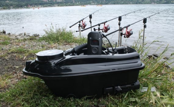 L’unione di passione, rispetto per la natura e brivido della sfida è la motivazione per cui milioni di pescatori si approcciano ogni anno al carpfishing, alla ricerca dei migliori spot per la cattura dei migliori esemplari di carpa. Questo sport è condizionato da moltissimi fattori e ciò ha spinto il mercato delle esche a differenziarsi in maniera notevole, tanto da rendere difficile il destreggiarsi tra i numerosi tipi di aromi, nutrienti, colori e forme, soprattutto per chi è alle prime armi. Così chi inizia a praticare il carpfishing si ritrova a scegliere tra una vasta gamma di prodotti, orientando la propria scelta sulle opzioni più costose, percepite come sinonimo di qualità e quindi di successo garantito oppure a guardare decine e decine di video-tutorial per preparare esche e pasture fai da te, concentrandosi erroneamente per lo più su un unico aspetto del carpfishing, ossia la qualità del cibo per le carpe. Prestare attenzione solo alle materie prime è tuttavia sbagliato in quanto il carpfishing è fatto anche da una buona dose di strategia, che non è necessariamente sinonimo di inganno ma di apertura mentale nei confronti di un mercato di accessori per la pesca che è in continua evoluzione e a cui molti si affidano per aumentare le probabilità di cattura, spinti sia dalla curiosità di sperimentare nuove tecniche in grado di agevolare la propria attività e sia dalla componente ludica che questi apparecchi tecnologici creano. Il barchino per carpfishing è una delle numerose innovazioni tecnologiche che oggi stanno rivoluzionando questo ramo della pesca, ma è anche una fra le più discusse perché è stata accolta dagli appassionati di pesca con atteggiamenti molto diversi tra di loro. Da una parte c’è chi sostiene che il barchino per carpfishing sia una delle tante invenzioni superflue che cercano di facilitare la pesca in modo sleale nei confronti del pesce e degli altri pescatori, mentre dall’altra parte sempre più appassionati hanno abbracciato la modernità di questo strumento accogliendolo con molto entusiasmo. Può tuttavia un accessorio come il barchino per carpfishing essere veramente catalogato come un mezzo d’inganno più di altri attrezzi che hanno lo stesso valore nella pesca, come per esempio l’ecoscandaglio? La verità è che non esiste attrezzatura sbagliata se non quella che è accertato possa fare del male al pesce e non esiste pescatore sleale tranne colui che non tutela le risorse ittiche e i ritmi naturali dell’ecosistema. Prima di passare in rassegna le principali componenti tecniche che differenziano un barchino per carpfishing dall’altro e che conseguentemente determinano l’appartenenza a diverse fasce di prezzo, bisogna chiarire il ruolo principale che questo attrezzo gioca nella pesca: quello di trasportare e disperdere la pastura nell’acqua, posizionando la lenza in quell’area strategica, in cui si creerà un’affluenza massiccia di carpe. Sul mercato ne esistono di vari modelli, dal barchino per carpfishing di ultima generazione che include componenti come l’ecoscandaglio a quello senza accessori aggiuntivi e quindi di prezzo chiaramente più contenuto, il quale fornisce le funzionalità principali. Ciò che accomuna le diverse tipologie di barchino è l’impiego che questi hanno nella pasturazione, ma anche alcune caratteristiche tecniche come il telecomando a medio-lunghe distanza, la resistenza alle onde, una batteria durevole e una certa robustezza nonostante il peso contenuto. Per quanto riguarda la compartimentazione del carico trasportato, la capacità di immagazzinamento e la sequenza di rilascio, il barchino per carpfishing presenta diverse opzioni: la quantità di pastura che può essere immagazzinata può raggiungere diversi chilogrammi e può essere suddivisa in più vani che consentono di pasturare in varie direzioni, mentre il suo rilascio può avvenire appena raggiunta l’area di pasturazione oppure in un momento secondario per mezzo di un apposito gancio azionato attraverso il telecomando. Questo strumento inoltre può avere diversi livelli di velocità e si sposta grazie a delle eliche, le quali sono dotate di un sistema di protezione che impedisce l’accumulo di detriti e il danneggiamento delle componenti meccaniche. Sia le eliche che il motore sono progettati al fine di produrre poco rumore durante il movimento per non spaventare e allontanare i pesci. Tra le varie funzionalità si enumerano anche il GPS in grado di registrate la posizione di pesca e la cui estensione viene integrata nella modalità di autopilota, in virtù della quale il barchino per carpfishing si sposterà in autonomia grazie al percorso memorizzato tra il punto di partenza e il punto di arrivo, garantendo al pescatore un notevole risparmio di tempo. I barchini più avanzati hanno anche un ecoscandaglio integrato in grado di rilevare pesci di diversa misura, offrendo una panoramica del fondale per individuare così gli spot più interessanti; grazie a diversi sensori, alcuni possono anche rilevare alcuni parametri importanti per la sessione di pesca come la temperatura dell’acqua e la pressione atmosferica, che giocano un ruolo fondamentale nel determinare l’attività delle carpe. Risultano chiari, dunque, i benefici che il barchino per carpfishing apporta a questa tipologia di pesca grazie alle sue numerose caratteristiche che non fanno altro che agevolare e automatizzare la pasturazione con notevoli risparmi di tempo ed energie. Si deve notare infine che questo strumento non rappresenta che un semplice pezzo del puzzle, il cui completamento e successo non può che essere raggiunto solo tramite la giusta combinazione e incastro degli altri pezzi, perché la sfida decisiva rimane quella tra il pescatore e la carpa